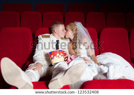 Wedding: kissing bride and groom posing as spectator in the cinema