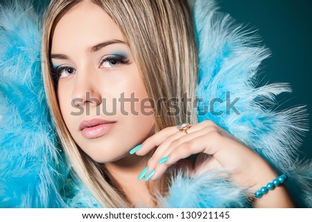 Closeup portrait of a pretty young and happy blonde woman with blue feathers on the neck