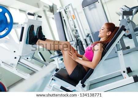 Attractive young fitness model works out on training apparatus inside in fitness center