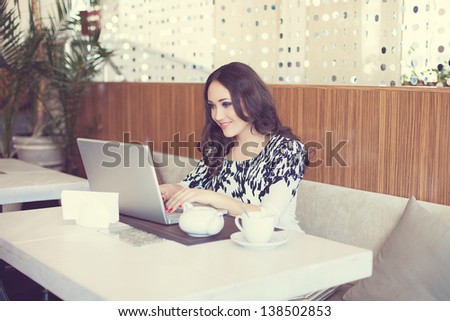Businesswoman drinking tea and using computer in a coffee