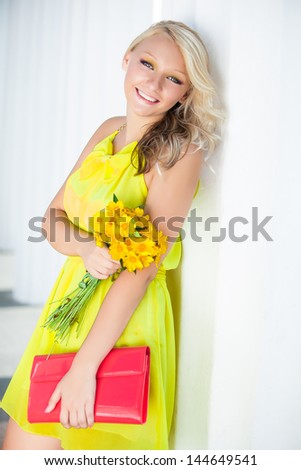 Happy young woman with a yellow bunch of flowers