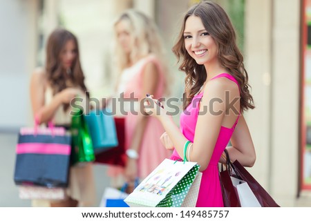 Happy shopping woman with a group of friends at the background
