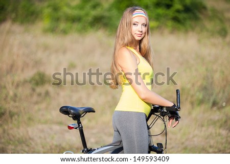 Attractive young model on bicycle standing on road. Cycle gear for cyclist trains for fitness.