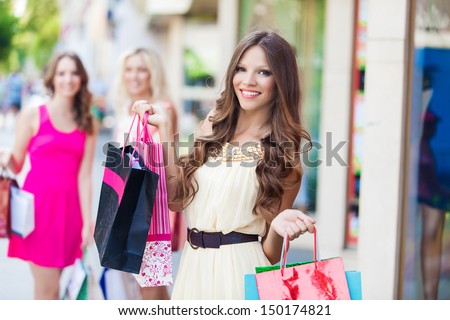 Shopping woman holding bags with a group of friends at the background