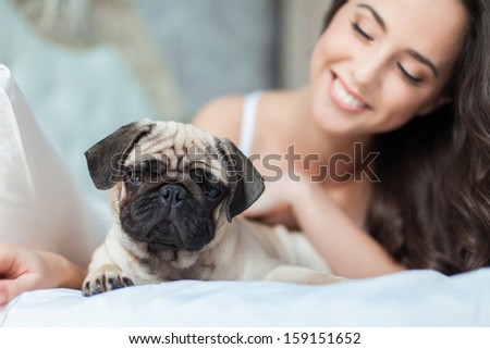 Attractive young girl with dog while laying on bed, focus on a dog