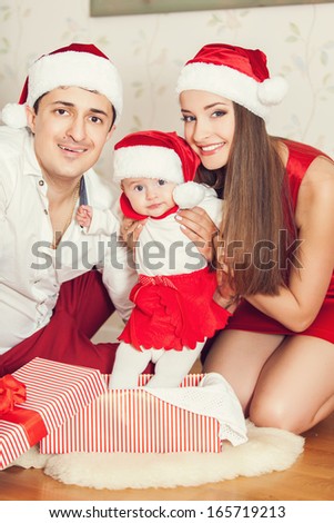 Portrait of happy family with cute baby in suit of Santa\'s little helper