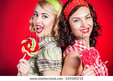 Beautiful pinup girls with lollipop on red background