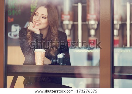 Young woman drinking coffee sitting indoor in urban cafe. Cafe city lifestyle. Casual portrait of teenager girl. Toned.