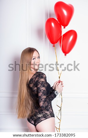 A young woman holding a heart-shaped balloon in studio