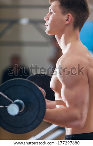 Profile of a young man working out in the gym