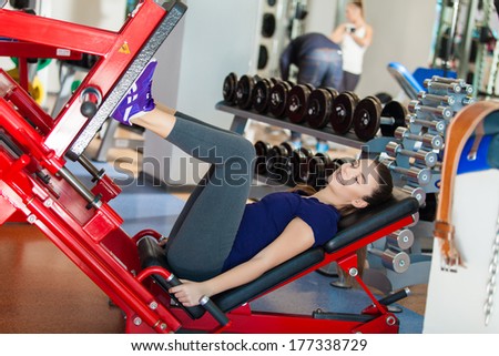 Young girl works out on training apparatus inside in fitness center