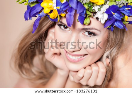 Young woman with a flower arrangement in her hair smiling at the camera