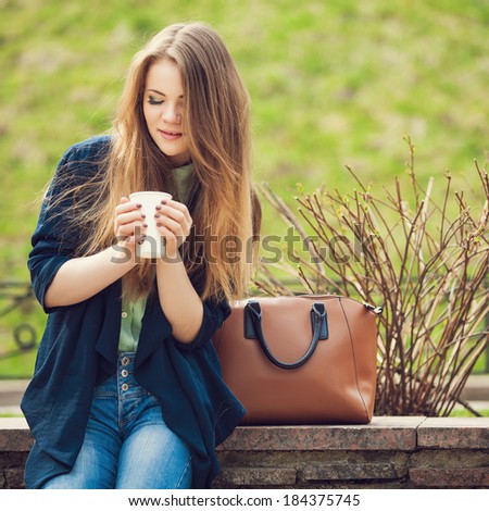 Cheerful fashionable woman holding coffee outdoors