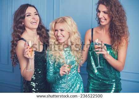 Three girls in evening dresses with champagne glasses - new year, celebration, friends, birthday concept