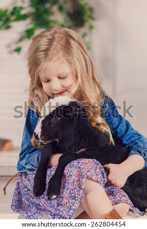 Little girl playing with a baby goat on a house porch