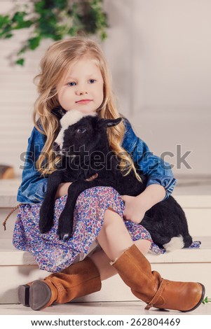 Little girl playing with a baby goat on a house porch
