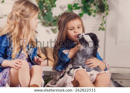 Little girls playing with a baby goat on a house porch