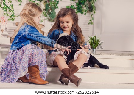 Little girls playing with a baby goat on a house porch