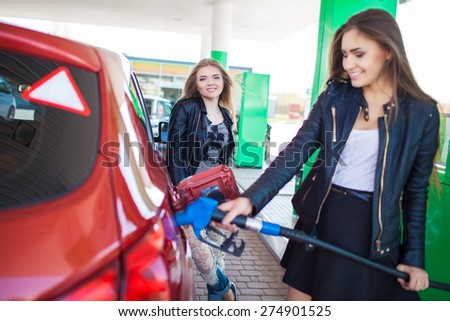 Happy friends refuel car in gas station. Holiday trip of friends