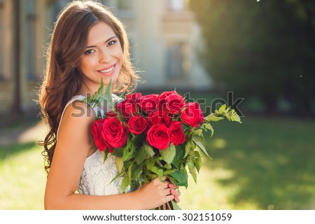 Smiling girl with bouquet of red roses