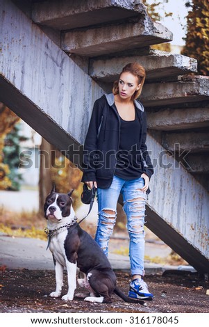 modern punk fashion, portrait of a beautiful model posing with American staffordshire terrier over street background