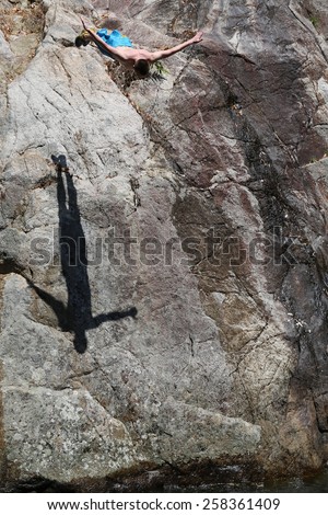Man jumping fish in water with high cliffs