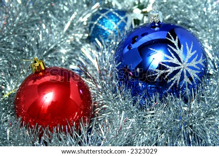 Two New Year\'s glass spheres of dark blue and red color with a pattern on a background of a christmas tinsel