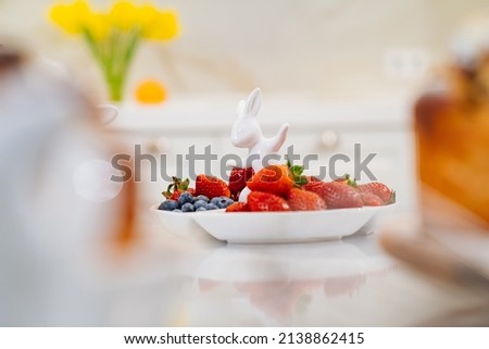 strawberries and blueberries in a white compartmental dish with rabbit. beautiful plate for appetizers, desserts and fruits. berries for the holiday and for every day. selective focus 商業照片 © 