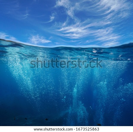 Seascape, air bubbles underwater sea and blue sky with cloud, split view over and under water surface, Mediterranean, France