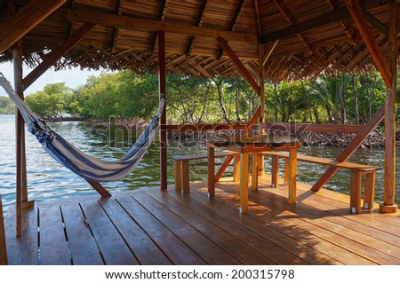 Peaceful scene on a palapa over water with hammock and a table, Caribbean sea
