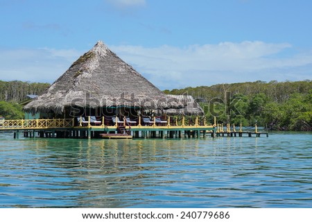 Tropical restaurant with thatch roof over water of the Caribbean sea, Central America