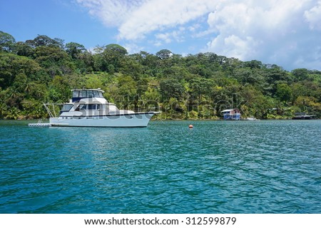 Yacht on mooring buoy with lush tropical coast in background, Caribbean Sea, Panama, Bocas del Toro, Central America