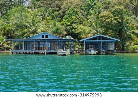 Tropical home and boat house over the sea with lush vegetation on the shore, Panama, Central America