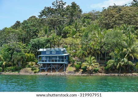 Oceanfront home on tropical shore with lush vegetation, viewed from the sea, Panama, Central America