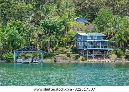 Coastal property on lush tropical shore with boats at dock and an house, Caribbean sea, Panama, Central America