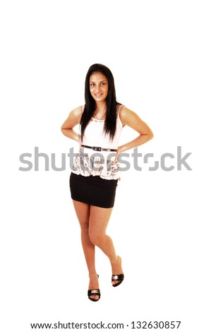 A slim teenager girl standing for white background, wearing a short black skirt and white blouse and high heels.