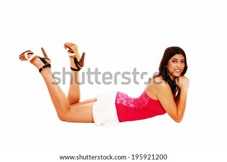 A beautiful young woman in a short white skirt and red blouse lying on the floor on her stomach, isolated on white background.