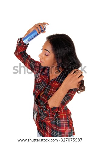 A profile image of a young african american woman in a colorful shirt\
spraying hair spray on her hair, isolated for white background.