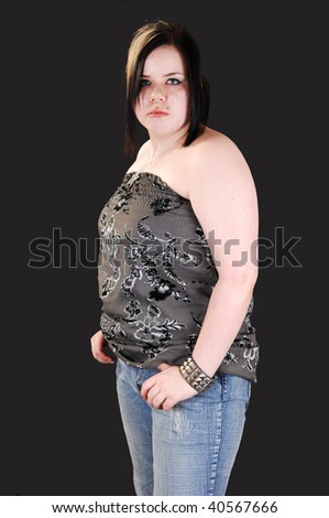 Young lovely girl in blue jeans and gray blouse, looking into the camera standing in the studio for black background.