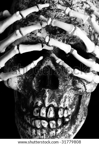 closeup of skeletal hands over eye sockets of skull