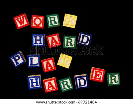 work hard, play harder - written in colorful wooden blocks, isolated on black
