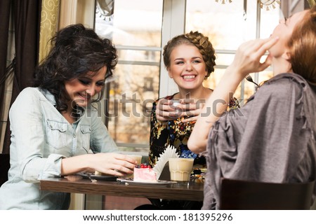Three women friends in cafe make dialogue and smile over joke