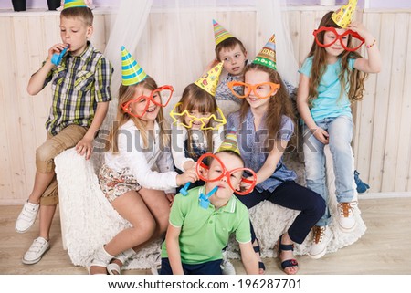 Large group of diversity looking kids, boys and girls sitting on the couch at home, hugging, smiling and laughing