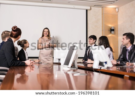 Pregnant business consultant answering a question during a meeting at office