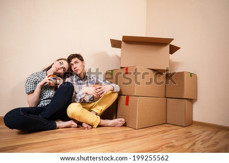 Young Couple with boxes of drinking coffee in the new apartment