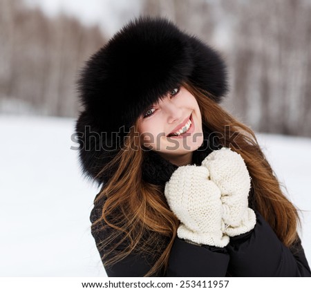 Portrait of happy young woman in luxury fur hat in winter