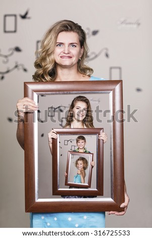 Happy mother holding portrait with her family each is located inside their own frame