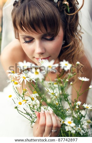 Young happy bride smells flowers camomile outdoors
