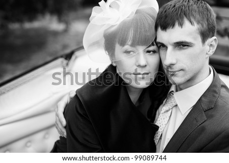 Newlyweds embraces outdoors. Groom and bride sit in the carriage