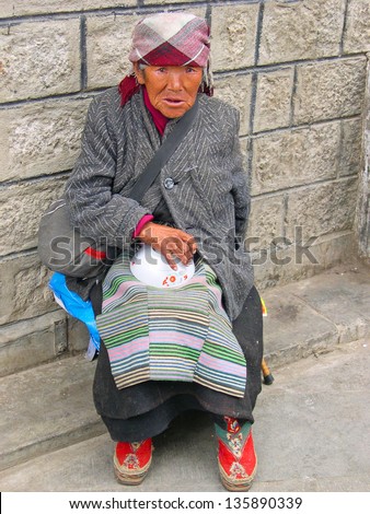 LHASA, TIBET-NOVEMBER 13:  old lady sitting in Barkhor Street. The ancient street is a symbol of Lhasa and a must see place for visitors. November 13, 2004 in Lhasa, Tibet
